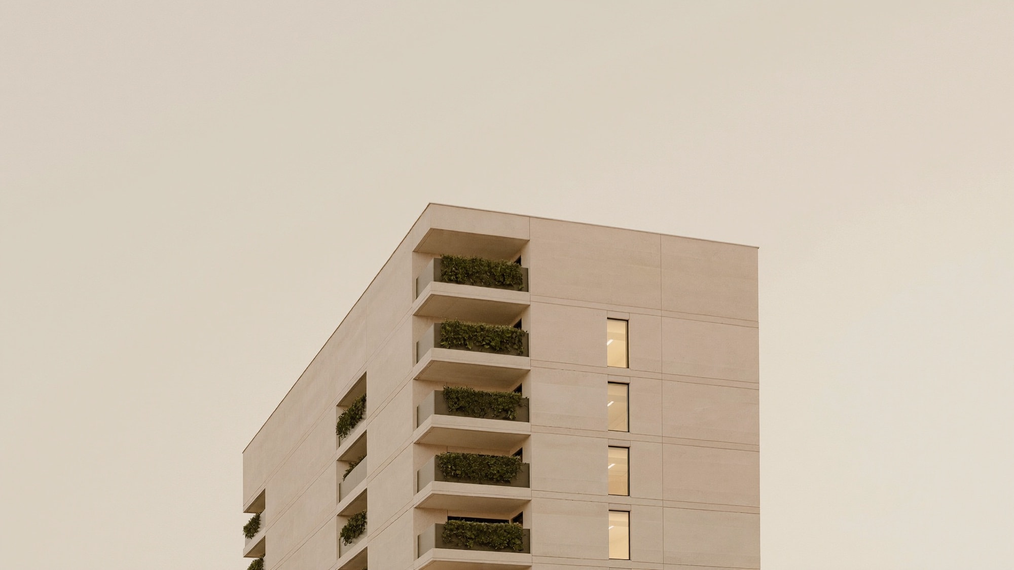 Modern apartment building with planted balconies and warmly lit homes